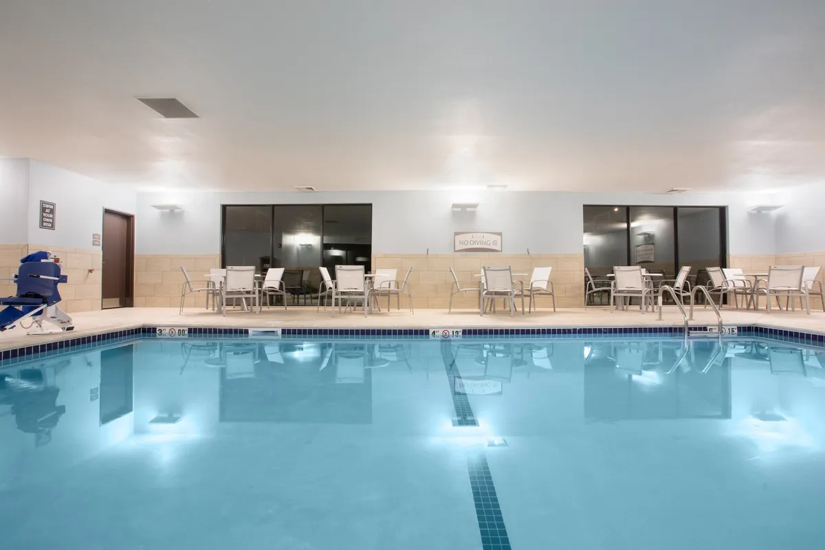 An inviting indoor swimming pool with sleek lounge chairs and expansive windows that let in abundant natural light. The tranquil atmosphere is perfect for relaxing swims or poolside conversations, emphasizing the resort-style amenity.